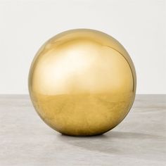 a large golden ball sitting on top of a white table next to a gray wall