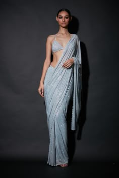 Editor's Note A demure look for your traditional occasions in this embellished pre-draped sari and top, beautifully crafted with crystal beads on the edges paired with cape Fabric: Net Color: S... Luxury Silver Lehenga For Festivals, Luxury Silver Designer Wear Blouse Piece, Luxury Designer Silver Blouse Piece, Luxury Silver Traditional Wear For Puja, Luxury Cutdana Saree For Eid, Luxury Silver Choli With Sheer Dupatta, Luxury Silver Traditional Wear, Luxury Chikankari Embroidery Pre-draped Saree For Party, Luxury Saree Skirt For Party Wear