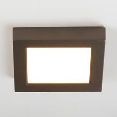 a close up of a square light fixture on a white wall with a black frame