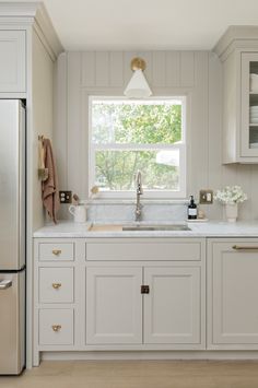 a kitchen with white cabinets and an open window