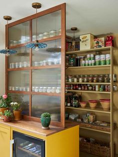 a kitchen with yellow cabinets and shelves filled with jars, spices, and other items