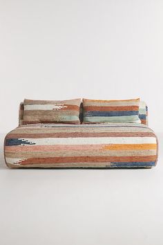 a multicolored striped couch sitting on top of a white floor next to a wall