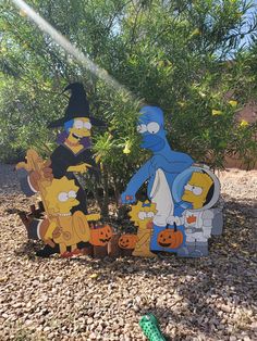 three cardboard cut outs of the simpsons characters in front of a tree with pumpkins