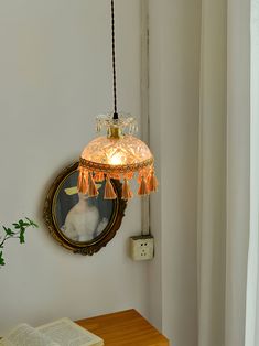 a lamp hanging from the side of a wall next to a book on a table