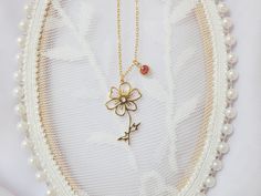 a necklace with a flower on it is hanging from a white beaded display case