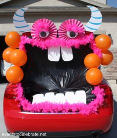 the trunk of a car decorated with pink and orange decorations, including fake teeth and horns