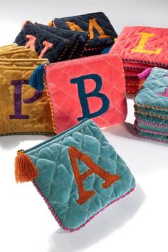 several colorful handbags with letters and tassels on them