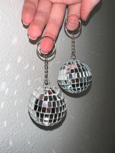 a pair of disco ball keychains being held by a person's hand