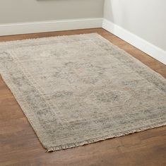 a beige rug with fringes on the floor next to a wall in a room