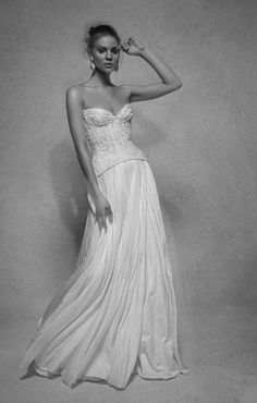 a woman in a long white dress posing for the camera with her hand on her head