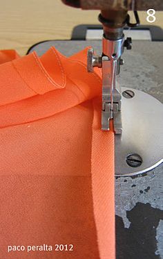 the sewing machine is working on an orange shirt