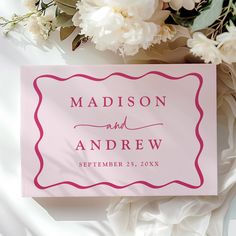 a pink and white wedding sign with flowers in the background on top of a bed