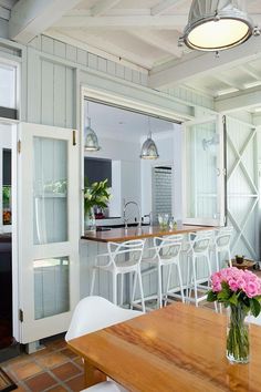 a kitchen and dining room area with white chairs, wood table and bar stools