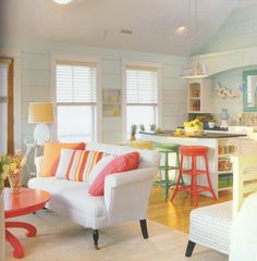 a living room filled with furniture next to a kitchen counter and breakfast nook area