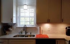 a kitchen with white cabinets and a black stove top oven next to a sink under a window