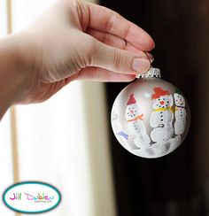 a hand holding a christmas ornament with snowmen on it