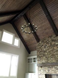 a living room with a stone fireplace and wooden ceiling beams, along with a chandelier hanging from the ceiling