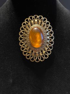 "Vintage Oval Amber Color Gem Brooch - has 3 layers of ornate gold color borders - it does not close very tight but it might on clothes - normal wear and scratches - may have slight discoloration in places due to age - 2.5\" x 2\"" Antique Gold Oval Brooch, Antique Gold Oval Brooches, Antique Gold Brooch With Oval Cabochon, Antique Gold Oval Cabochon Brooch, Antique Gold Brooches With Oval Cabochon, Antique Gold Oval Cabochon Brooches, Ornate Gold Cabochon Brooches, Antique Gold Brooch With Cabochon Detail, Antique Gold Brooch With Cabochon