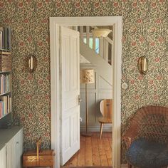 an open door leading into a room with floral wallpaper on the walls and wooden floors