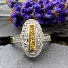 An Art Deco style ring in 9ct gold set with five round brilliant yellow sapphires surrounded by a deep Rhodium border set with eleven Round brilliant Diamond accents and two further Diamonds to the shoulders. Ornate pierced gallery. 9ct yellow gold shank. 375 Birmingham In excellent condition Will arrive gift boxed Free tracked shipping/UK next day delivery. Art Deco Gold Rings With Halo Setting, Gold Art Deco Ring With Halo Setting, Gold Art Deco Rings With Halo Setting, Gold Oval Sapphire Ring In Art Deco Style, Hallmarked Yellow Diamond Ring, Art Deco Gold Sapphire Ring With Rose Cut Diamonds, Gold Art Deco Cluster Ring, Art Deco Hallmarked Yellow Gold Cluster Ring, Art Deco Sapphire Ring In Yellow Gold