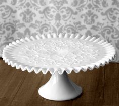 a white cake plate sitting on top of a wooden table