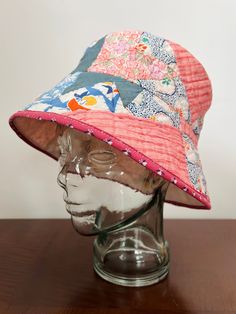 "Pretty in pink! This sweet sun hat was crafted from a hand stitched 1930s Cake Stand quilt made from cheerful feedsacks and quilting cotton in serene pinks and blues Charming floral fabrics, complemented by pink on pink ticking Seams and raw edges bound with homemade bias tape made from 1990s pink, white, and ble calico fabric  Unlined, lightweight, soft, slightly lampshade shaped  In excellent condition with no issues whatsoever  Measurements: 22\" inner circumference  2-3/4\" tall band 3.5\" Pink Bohemian Sun Hat For Garden Party, Bohemian Pink Sun Hat For Garden Party, Pink Bucket Hat For Garden Party, Pink Reversible Bucket Hat With Curved Brim, Whimsical Pink Bucket Hat, Retro Pink Cotton Hat, Pink Cotton Sun Hat With Curved Brim, Pink Brimmed Cotton Sun Hat, Vintage Pink Sun Hat For The Beach