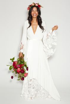 a woman in a white wedding dress holding flowers and a flower crown on her head