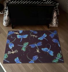 a black rug with blue butterflies on it in front of a dresser and bedding