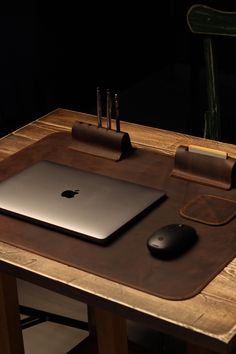 an apple laptop computer sitting on top of a wooden desk next to a mouse pad