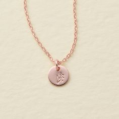 a pink necklace with a small disc on it