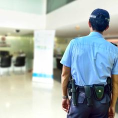 a police officer is standing in an airport looking at the luggage carousels behind him