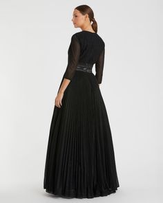 a woman wearing a black dress with sheer sleeves and pleated skirt, back view