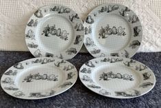 four black and white plates sitting on top of a carpeted floor next to a wall