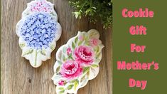 two cookies decorated with flowers on top of a wooden table and the words cookie gift for mother's day