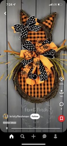 an orange and black cat wreath hanging on a wooden wall with the words happy halloween written below it