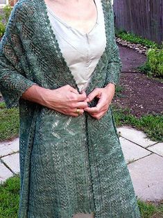 a woman standing in the grass wearing a green cardigan