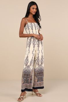 Slip into your most summery sandals and the Lulus Charming Attitude Ivory Paisley Smocked Wide-Leg Jumpsuit for a breezy fit that's as cute as it is comfy! Sleek, lightweight woven fabric boasts a sunny paisley print as it falls from adjustable spaghetti straps, shaping a smocked bodice with a straight neckline. Fitted waist tops wide legs that end at ankle-length hems. Fit: This garment fits true to size. Length: Floor length. Size medium measures 57" from adjustable straps to hem. Inseam: 29.0 Bohemian Jumpsuits And Rompers With Smocked Back For Spring, Bohemian Style Smocked Bodice Summer Jumpsuits And Rompers, Bohemian Jumpsuits And Rompers With Smocked Bodice For Summer, Summer Bohemian Jumpsuits And Rompers With Smocked Back, Bohemian Summer Jumpsuits And Rompers With Smocked Back, Casual Summer Jumpsuits And Rompers With Smocked Back, Casual Patterned Jumpsuits And Rompers For Vacation, White Summer Jumpsuit With Smocked Back, Bohemian Jumpsuits And Rompers With Smocked Bodice For Vacation