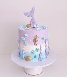 a purple and blue cake decorated with seahorses, seashells and mermaid tails