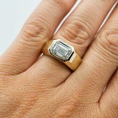 a woman's hand with a ring on it that has an emerald stone in the center