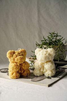 two stuffed animals sitting next to each other on top of a white cloth covered table