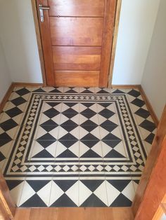 a black and white tiled floor in front of a wooden door