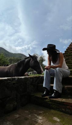 a woman sitting on steps next to a horse