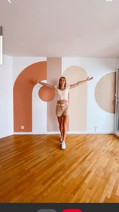 a woman is standing in an empty room with her arms outstretched and legs spread out