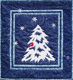 a quilted christmas tree with snowflakes and a red bird on it's back