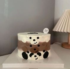 a white cake sitting on top of a table next to a lamp