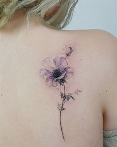 the back of a woman's shoulder with a single flower tattoo on her upper arm