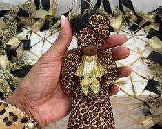 a hand holding a leopard print ornament in front of a gold and black background