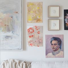 several paintings hang on the wall above a couch