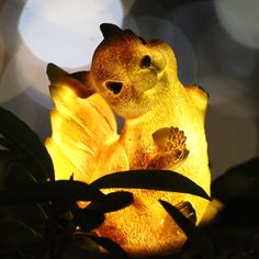 a yellow teddy bear sitting on top of a flower next to a light bulb in the dark