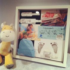 a stuffed animal next to a baby's hand and foot prints in a shadow box